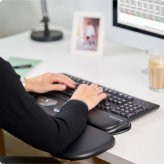 Detailaufnahme mit einer Frau an ihrem ergonomischen Buero-Arbeitsplatz mit einer ergonomischen Tischlehne fuer den Schreibtisch.
